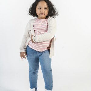 Full-body portrait of a stylish young girl in a casual outfit posing confidently in a studio.