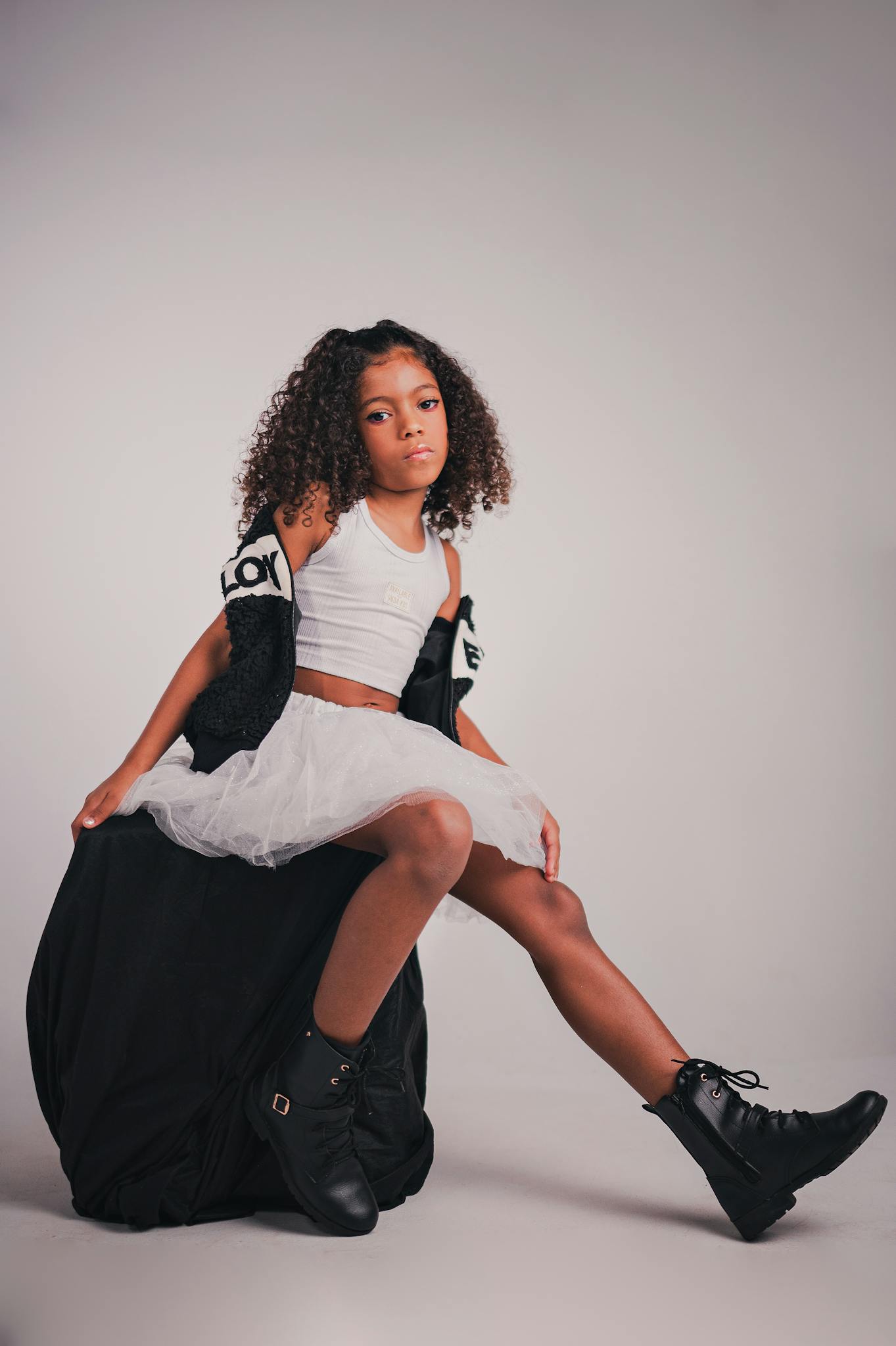 Young girl in a chic outfit striking a pose in a studio setting. Perfect for fashion and lifestyle themes.